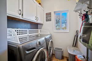 Laundry area featuring tile patterned flooring, separate washer and dryer, and cabinets