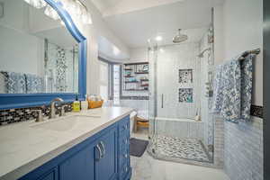 Bathroom with walk in shower, vanity, tile walls, and tile patterned flooring