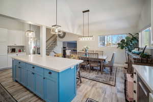 Kitchen featuring vaulted ceiling, pendant lighting, white cabinets, and blue cabinetry