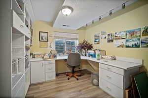 Office space featuring light hardwood / wood-style floors, a textured ceiling, and built in desk