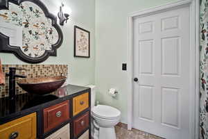 Bathroom with tile patterned flooring, vanity, decorative backsplash, and toilet