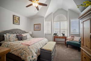 Carpeted bedroom with ceiling fan and lofted ceiling