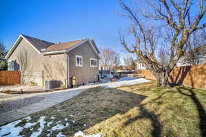 Rear view of property with a yard and central AC