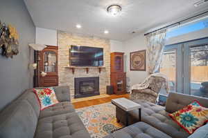 Living room with a textured ceiling, light hardwood / wood-style flooring, and a fireplace