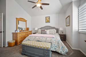 Bedroom with ceiling fan, lofted ceiling, and dark colored carpet