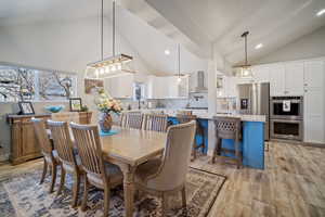 Dining area featuring high vaulted ceiling and light hardwood / wood-style flooring