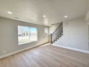 Unfurnished living room featuring a textured ceiling and light wood-type flooring