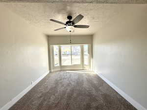 Carpeted spare room featuring ceiling fan and a textured ceiling