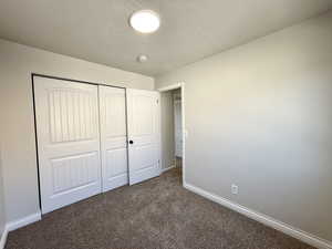 Unfurnished bedroom with a closet and dark colored carpet