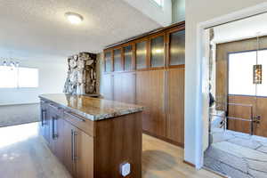 Kitchen featuring decorative light fixtures, light stone counters, a center island, and a chandelier