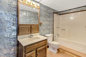 Full bathroom featuring hardwood / wood-style flooring, toilet, vanity, and  shower combination