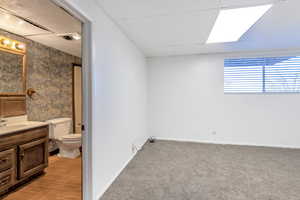 Bathroom with toilet, a drop ceiling, and vanity