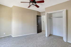 Bedroom featuring light carpet, ceiling fan, a closet, and a textured ceiling