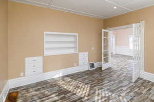 Unfurnished room with hardwood / wood-style floors, built in features, and french doors