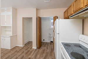 Kitchen with light hardwood / wood-style floors and white range with electric cooktop