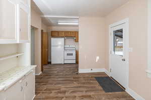 Kitchen and dining room with extractor fan, white appliances, tile counters, and dark hardwood / wood-style floors