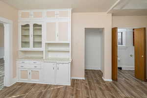 Kitchen hutch featuring wood-type flooring and white cabinets