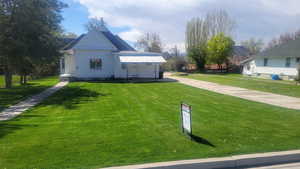View of front of property featuring a front yard and concrete driveway