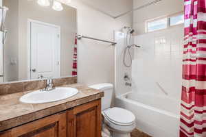 Full bathroom with toilet, shower / bath combination with curtain, and vanity