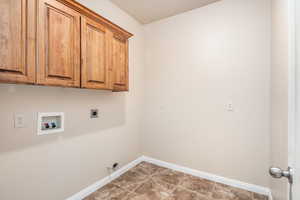 Washroom featuring hookup for a washing machine, cabinets, and hookup for an electric dryer