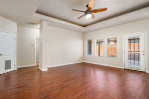 Unfurnished room with ceiling fan, a tray ceiling, and dark hardwood / wood-style floors