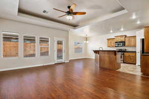 Kitchen featuring appliances with stainless steel finishes, a center island, decorative light fixtures, a kitchen bar, and a tray ceiling