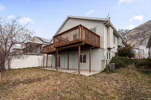 Back of property with a deck with mountain view, a patio area, a yard, and central AC