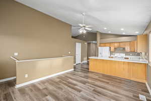 Kitchen featuring kitchen peninsula, ceiling fan, white appliances, light hardwood / wood-style flooring, and sink