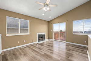 Unfurnished living room featuring ceiling fan, vaulted ceiling, a tile fireplace, and hardwood / wood-style flooring