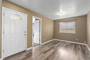 Entryway with wood-type flooring and a textured ceiling