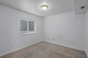 Empty room featuring light carpet and a textured ceiling