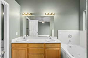 Bathroom with ceiling fan, a tub to relax in, and vanity