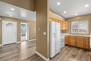 Kitchen featuring light wood-type flooring, sink, and white appliances