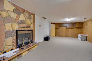 Basement with a stone fireplace, a textured ceiling, and carpet flooring