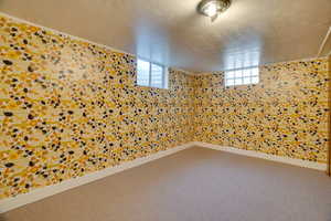 Carpeted empty room featuring a textured ceiling