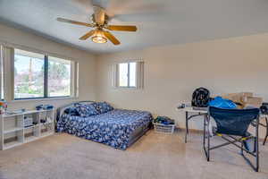 Bedroom with a textured ceiling, ceiling fan, and carpet flooring