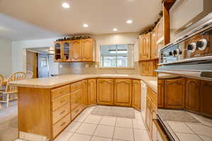 Kitchen with sink, backsplash, kitchen peninsula, white dishwasher, and light tile patterned floors