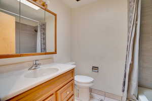 Full bathroom with toilet, tile patterned flooring, shower / tub combo, and vanity