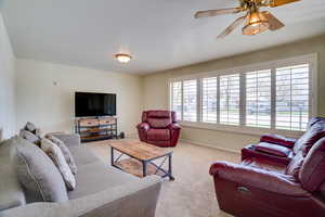 Carpeted living room with ceiling fan