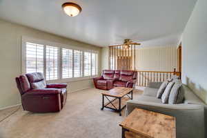 Living room with carpet floors, plenty of natural light, and ceiling fan