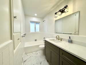 Updated full bathroom featuring toilet, tile walls, tiled shower / bath, and vanity