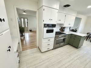 Kitchen with white cabinets, stainless steel range, and oven