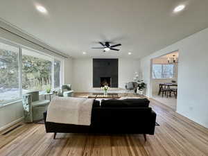 Living room with a large fireplace, a healthy amount of sunlight, and light wood-type flooring