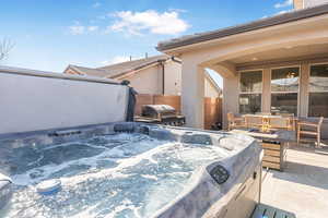 Snow covered patio with a hot tub and area for grilling