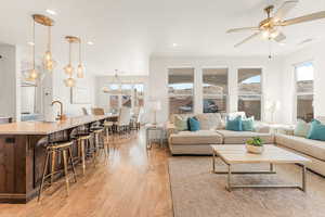 Living room featuring sink, ceiling fan with notable chandelier, a textured ceiling, and light wood-type flooring