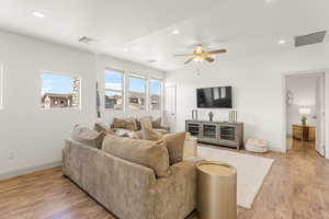 Living room with ceiling fan, hardwood / wood-style floors, and a textured ceiling