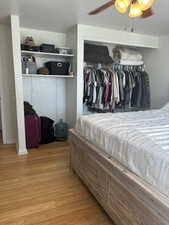 Bedroom with ceiling fan, wood-type flooring, and a closet