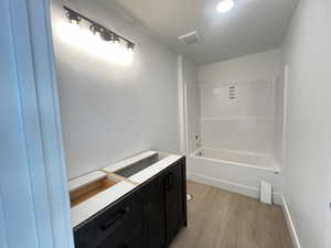 Guest Bathroom with vanity, bathing tub / shower combination, and hardwood / wood-style flooring