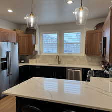 Kitchen with stainless steel appliances, hanging light fixtures, a sink, and brown cabinets