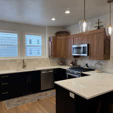 Kitchen with light wood finished floors, visible vents, appliances with stainless steel finishes, pendant lighting, and a sink